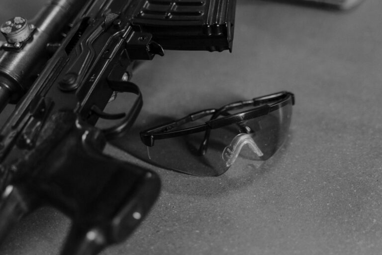 Detailed black and white photo of a rifle and safety glasses, highlighting firearm safety.